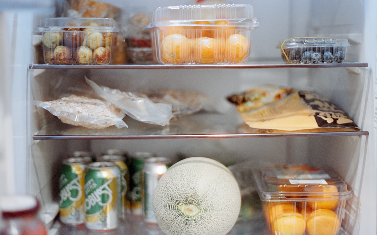 Various foods and drinks stocked inside an open refrigerator