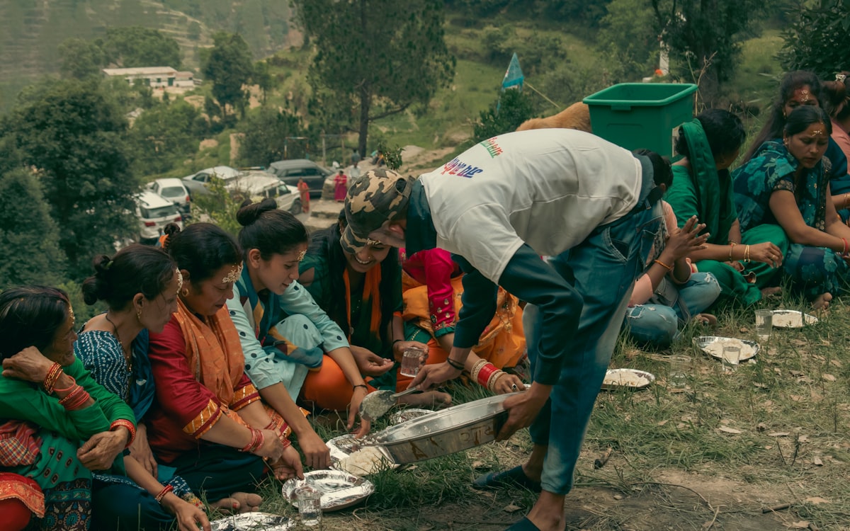 A person pouring a liquid into a container with a group of people