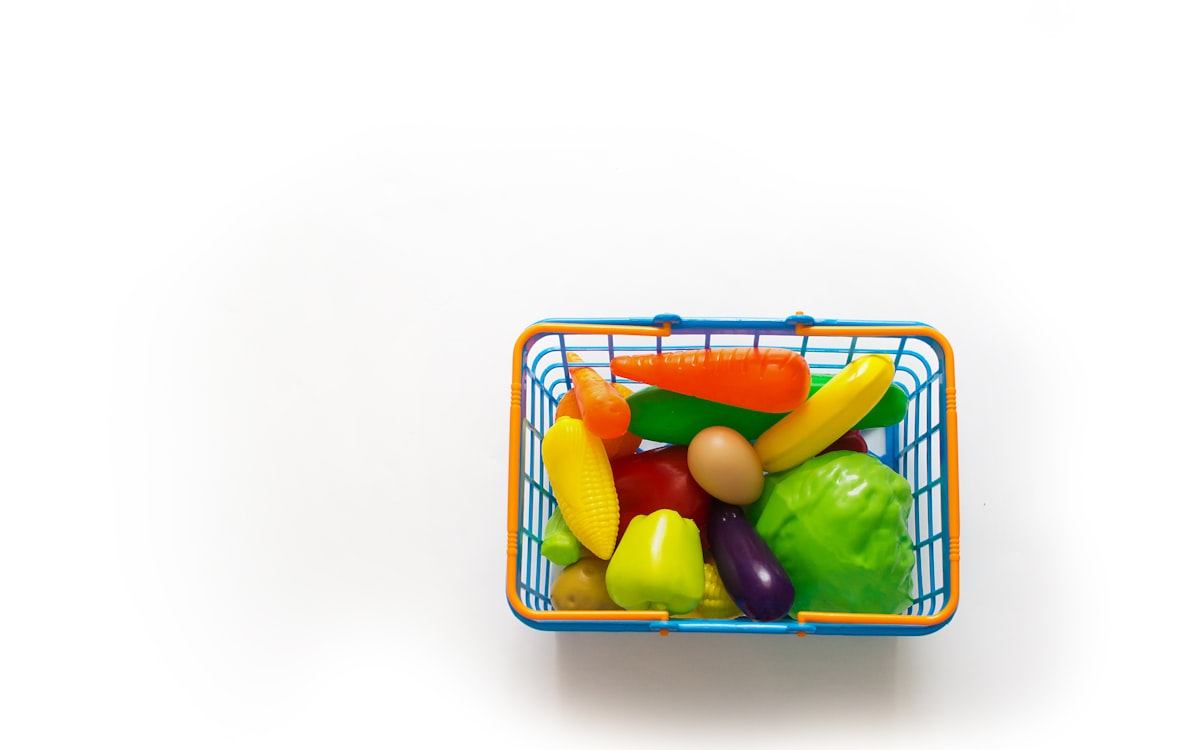 A basket of assorted fruits and vegetables on a white background