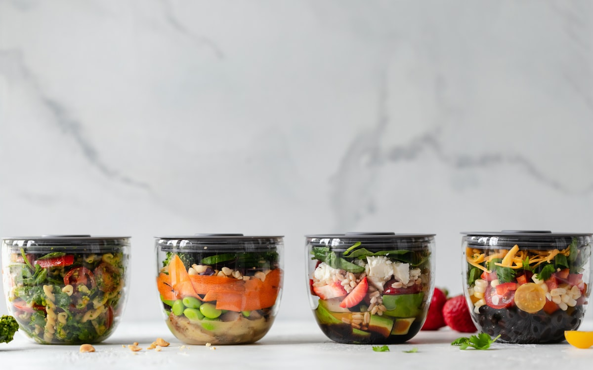 Four clear plastic bowls with vegetables