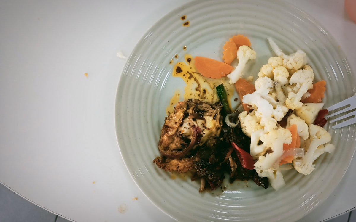 A white plate topped with meat and veggies