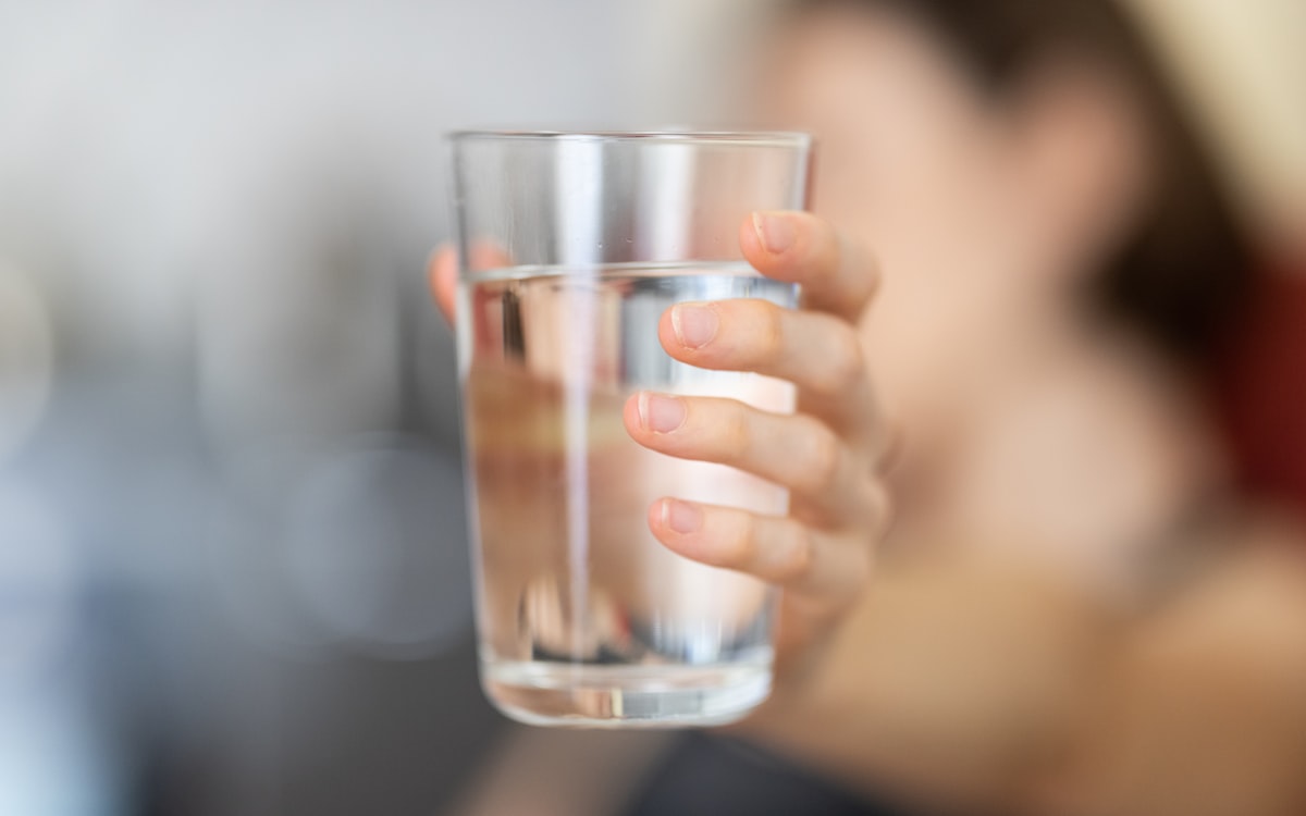 Person holding clear drinking glass