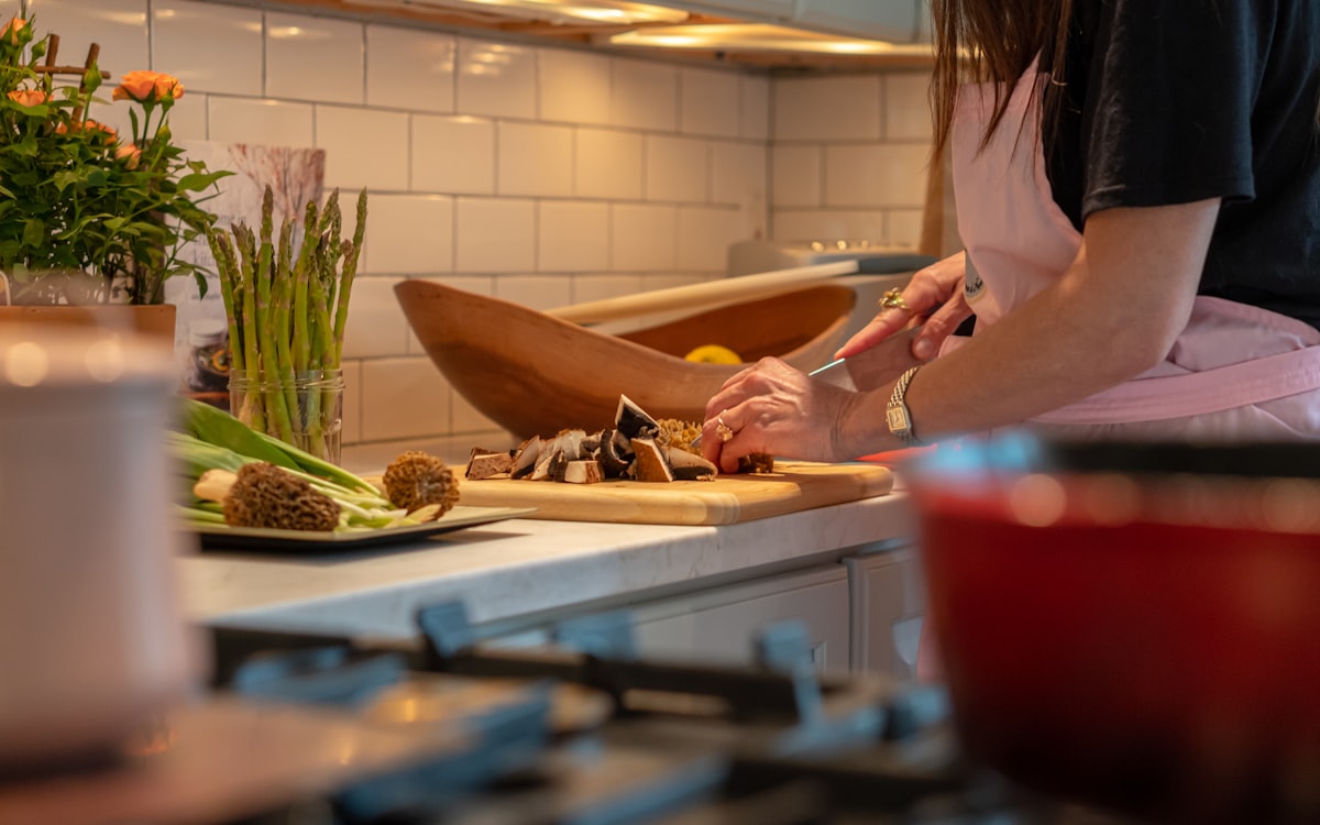 A woman in a kitchen chopping vegetables on a cutting board