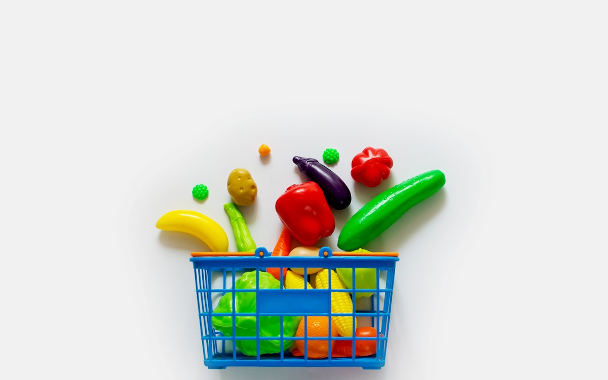 A toy shopping basket filled with lots of colorful toys