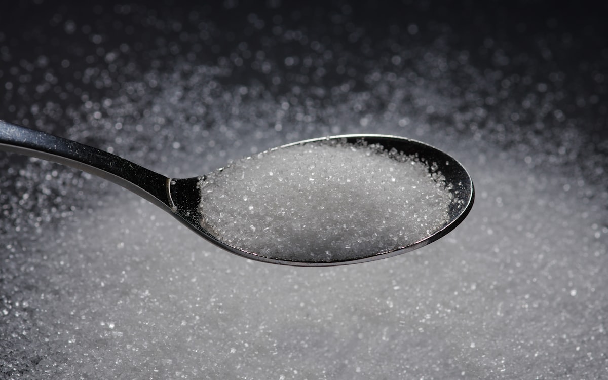 A spoon filled with sugar on top of a table
