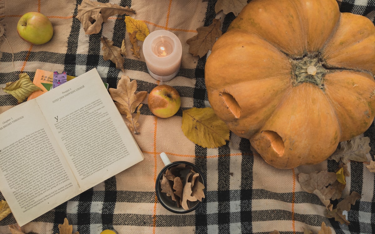A table topped with an open book and a pumpkin