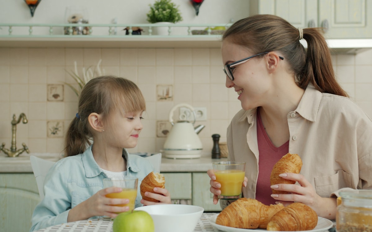 Mother and daughter enjoying breakfast with croissants
