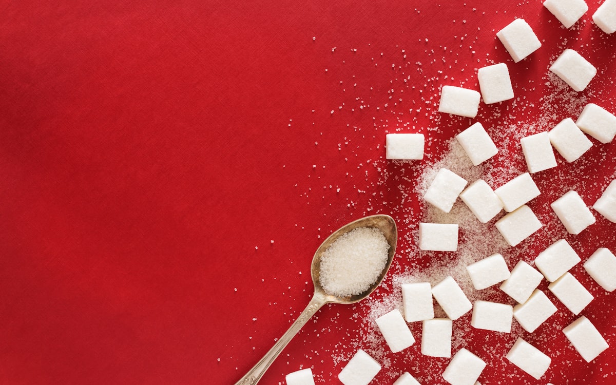 Sugar cubes and a spoon on a red surface