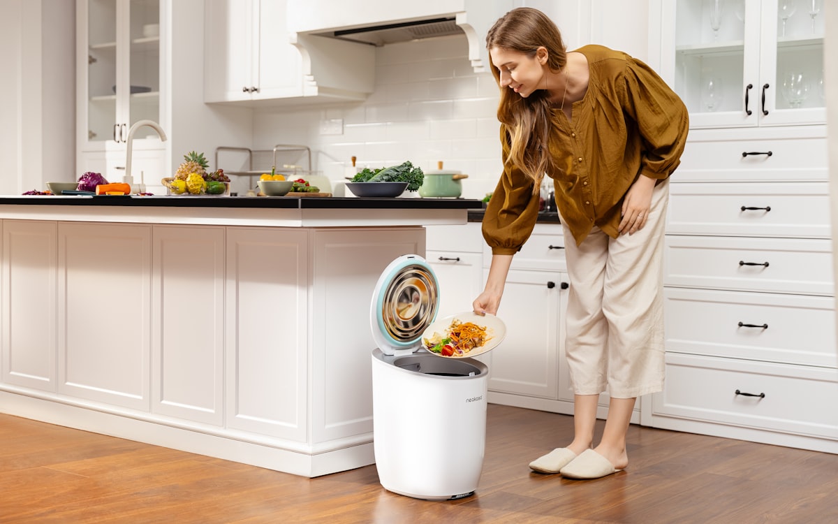 A woman standing next to a trash can in a kitchen