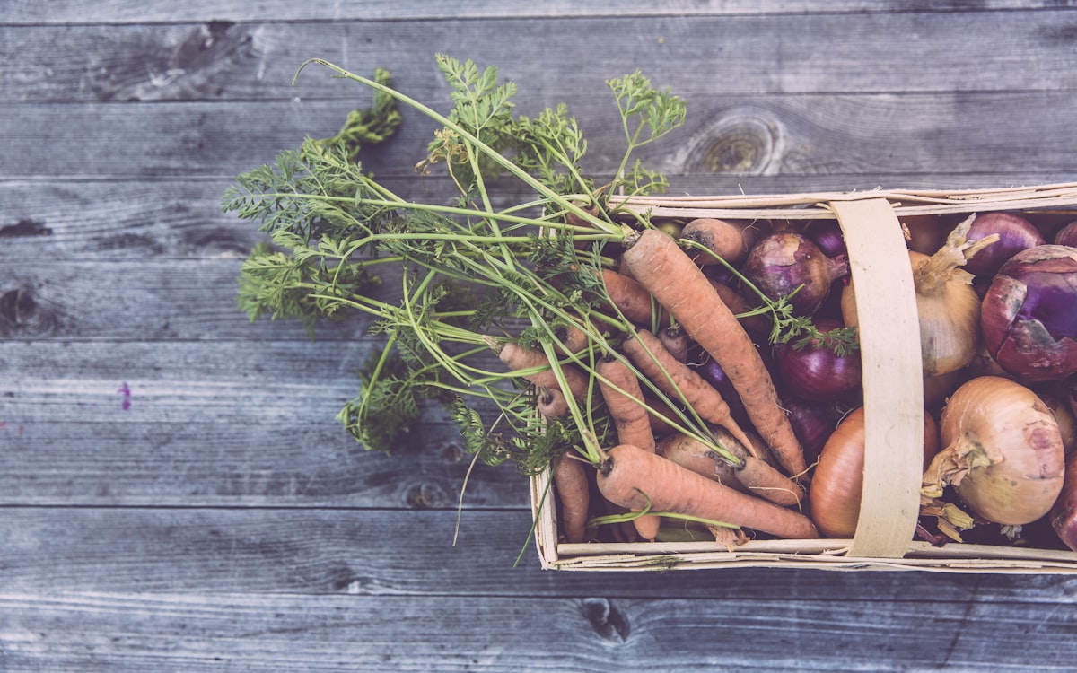 Carrots and onions in brown wicker basket